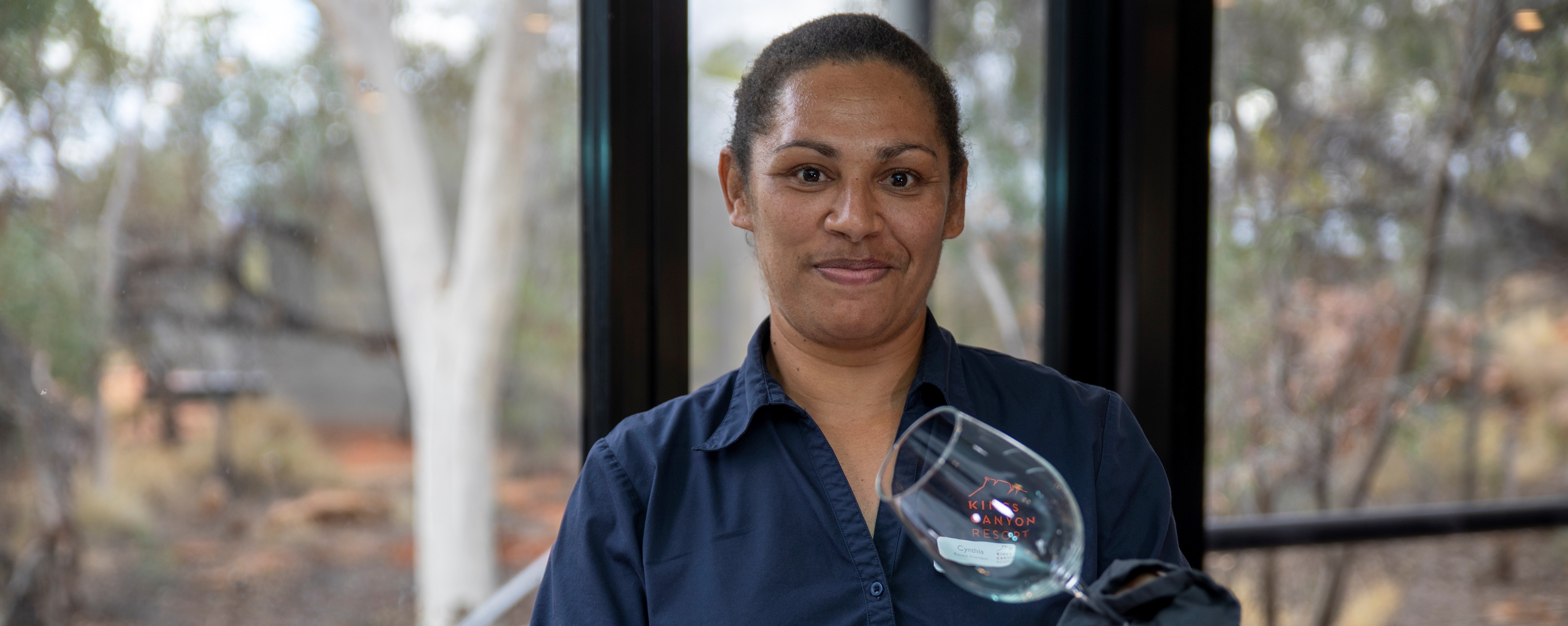 A woman standing in a restaurant cleaning a wine glass