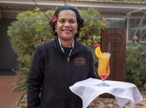 A woman standing serving a cocktail 